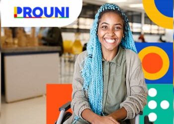 Estudante sorrindo em cadeira de rodas, com cabelo azul, ao fundo ambiente de universidade com logo do Prouni. Imagem: Gov.br