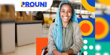 Estudante sorrindo em cadeira de rodas, com cabelo azul, ao fundo ambiente de universidade com logo do Prouni. Imagem: Gov.br