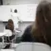 Estudantes assistem a aula de química em sala de aula, enquanto o professor escreve na lousa.
