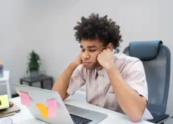 Jovem profissional desmotivado olhando para o laptop no escritório.