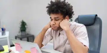 Jovem profissional desmotivado olhando para o laptop no escritório.