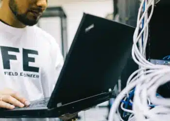 Técnico de TI trabalhando em um servidor com um laptop.