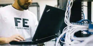 Técnico de TI trabalhando em um servidor com um laptop.
