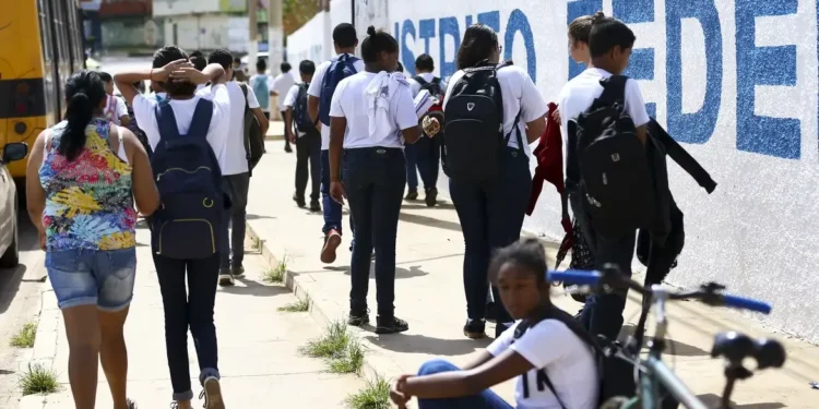  Grupo de estudantes de uniforme caminhando para a escola em um dia ensolarado.