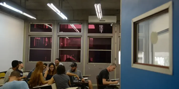 Grupo de estudantes universitários em sala de aula discutindo atividades acadêmicas.