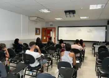 Estudantes assistindo aula em sala de aula, com foco no aprendizado em grupo.