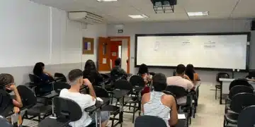 Estudantes assistindo aula em sala de aula, com foco no aprendizado em grupo.