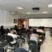 Estudantes assistindo aula em sala de aula, com foco no aprendizado em grupo.