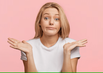 Mulher com expressão de dúvida, fazendo um gesto de encolher os ombros, com fundo rosa.