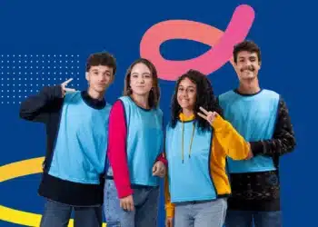 Grupo de jovens sorrindo, vestindo coletes azuis, posando para a foto.