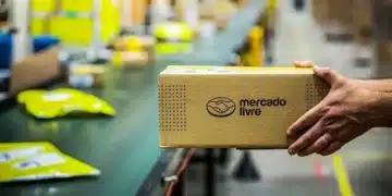 Pacote do Mercado Livre sendo manuseado em centro logístico, com esteira e pacotes ao fundo