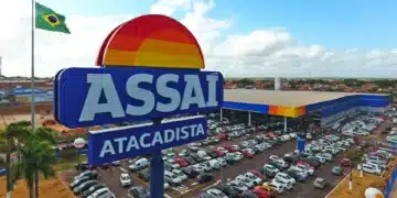 Fachada do Assaí Atacadista com estacionamento e bandeira do Brasil.