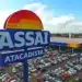 Fachada do Assaí Atacadista com estacionamento e bandeira do Brasil.