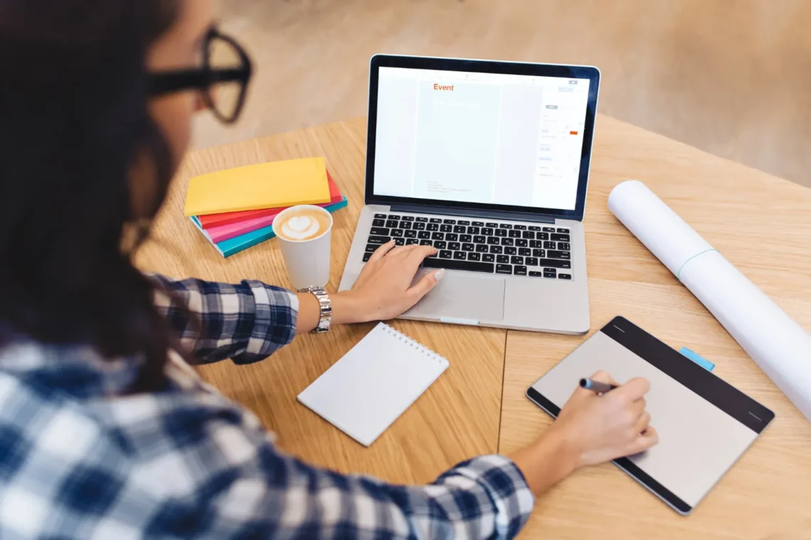 Mulher trabalhando em um laptop e mesa digitalizadora, representando a importância da presença online no personal branding