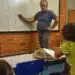 Professor explicando conteúdo no quadro para alunos em sala de aula.