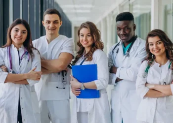 Equipe de profissionais da saúde sorrindo em um corredor de hospital.