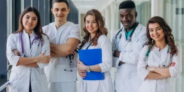 Equipe de profissionais da saúde sorrindo em um corredor de hospital.
