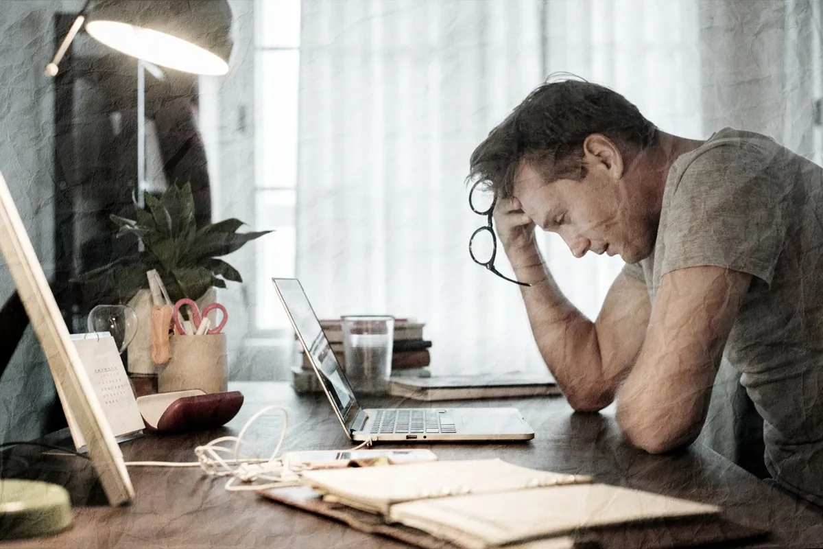 Homem reflexivo sentado à mesa, apreciando um momento de solidão.