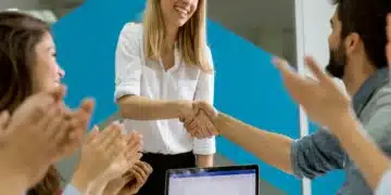 Funcionária recebendo reconhecimento e aplausos da equipe no ambiente de trabalho.
