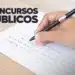 Mão segurando uma caneta enquanto preenche um cartão-resposta de prova objetiva, representando a realização de concursos públicos.