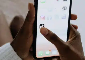 Pessoa segurando um smartphone com o aplicativo TikTok aberto, simbolizando o processo de ganhar dinheiro na plataforma.
