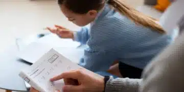Criança estudando matemática em casa com ajuda de um adulto.