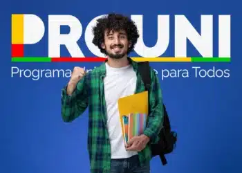 Estudante sorridente com mochila e cadernos na mão, diante do banner do PROUNI.
