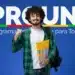 Estudante sorridente com mochila e cadernos na mão, diante do banner do PROUNI.
