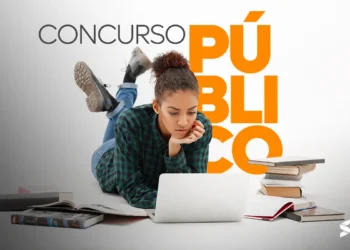 Mulher estudando para concurso público com laptop e livros ao redor.
