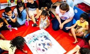 Crianças reunidas em círculo em uma atividade de leitura interativa com um grande livro ilustrado.