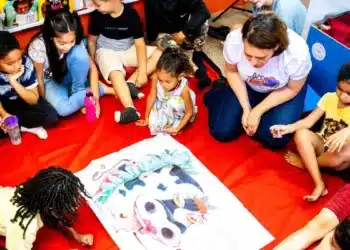 Crianças reunidas em círculo em uma atividade de leitura interativa com um grande livro ilustrado.