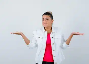 Mulher com expressão de dúvida e gesto de balança, representando incerteza sobre a grafia correta de "Mexer" ou "Mecher".