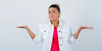 Mulher com expressão de dúvida e gesto de balança, representando incerteza sobre a grafia correta de "Mexer" ou "Mecher".