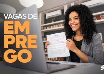 Mulher sorridente segura um contrato de trabalho durante uma entrevista online, com um notebook à sua frente e a frase "Vagas de Emprego" destacada na tela.