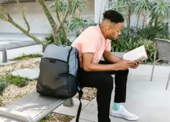 Estudante lendo livro ao ar livre, simbolizando o acesso à educação com a nova bolsa de R$ 200 do governo.
