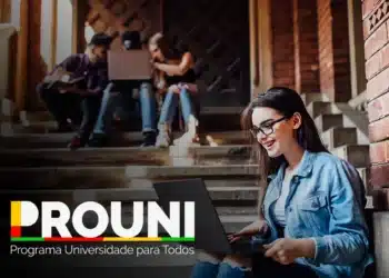 Jovem sorridente com laptop, estudando na universidade – ProUni.