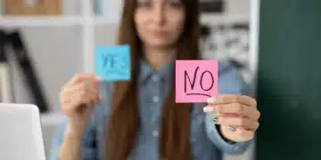 Mulher segurando dois papéis, um azul com "YES" e um rosa com "NO", simbolizando indecisão ou escolhas no trabalho.