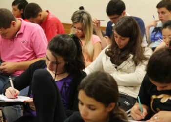 Jovens e adultos participando de uma sala de aula no contexto da EJA (Educação de Jovens e Adultos), com alunos focados em suas atividades.