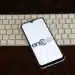 Imagem de um smartphone com o logo do Encceja 2025 exibido na tela, sobre uma mesa com um teclado branco ao fundo.