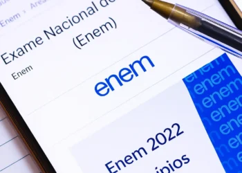 Smartphone screen displaying the Exame Nacional do Ensino Médio (Enem) website with a ballpoint pen in focus.