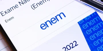 Smartphone screen displaying the Exame Nacional do Ensino Médio (Enem) website with a ballpoint pen in focus.