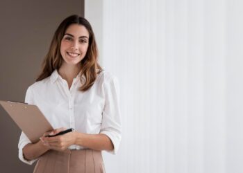 Mulher de negócios elegante, sorrindo enquanto segura uma prancheta com espaço para anotações.
