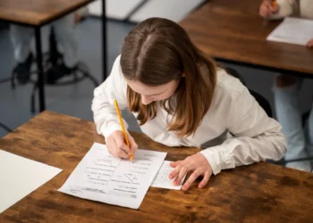 Estudante concentrada fazendo um teste escolar com um lápis, escrevendo respostas em uma folha.