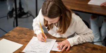 Estudante concentrada fazendo um teste escolar com um lápis, escrevendo respostas em uma folha.