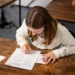 Estudante concentrada fazendo um teste escolar com um lápis, escrevendo respostas em uma folha.