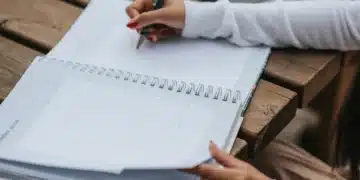 Pessoa escrevendo em um calendário em um dia tranquilo, com um caderno e caneta.