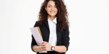 Mulher jovem com cabelo cacheado segurando documentos, pronta para começar estágio profissional.