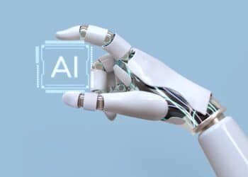 Mão robótica segurando um símbolo holográfico de inteligência artificial (AI) sobre fundo azul claro.