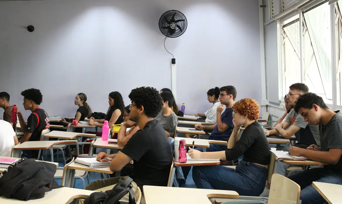 Jovens estudantes sentados em sala de aula, atentos e focados