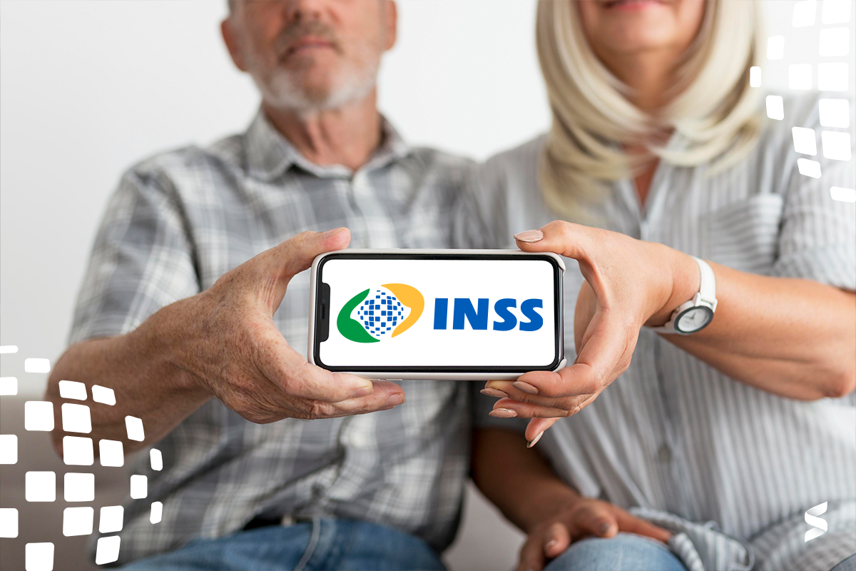 Casal idoso segurando celular com o logo do INSS na tela